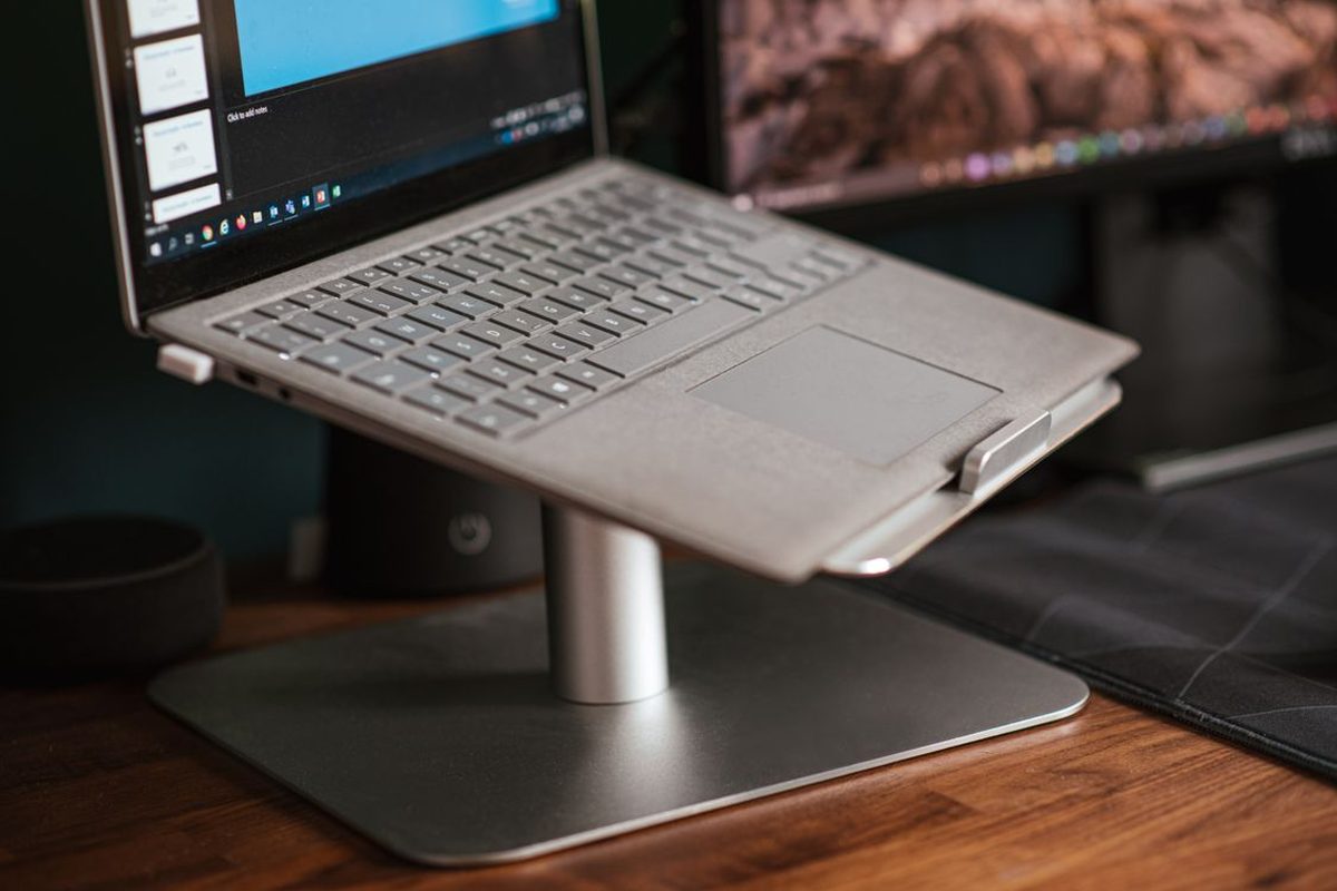 Representative photo: a laptop elevated on a silver metal stand on a wooden desk. Not the Roost V3.