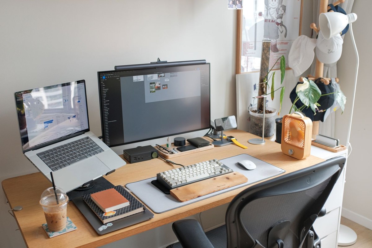 Tidy desk setup with a laptop on a stand beside an external monitor.
